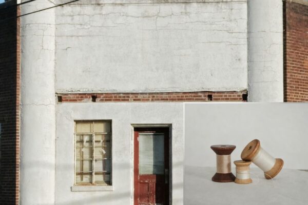 Fasad av gammal byggnad med fönster och dörr, med tre trådrullar i förgrunden.